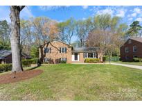 Charming brick home featuring a lush green lawn, mature trees, and classic black shutters at 3808 Severn Ave, Charlotte, NC 28210