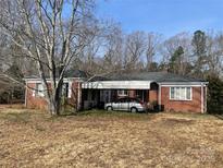 Charming red brick house with a covered parking area and mature trees in a wooded setting with blue skies at 501 Neelys Creek Rd, Rock Hill, SC 29730