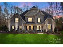 Charming two-story stone home with a lush green lawn and well-manicured landscaping provides great curb appeal at 518 May Green Dr, Clover, SC 29710