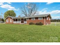 Charming brick home boasts a spacious front yard and inviting porch at 5643 Twinkle Dr, Concord, NC 28025