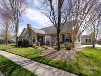 Charming single-Gathering home featuring a stone facade, mature landscaping, and a cozy front patio at 864 Ledgestone Ct, Fort Mill, SC 29708
