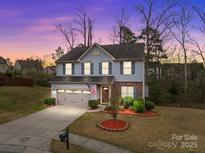Charming two-story home with blue siding, stone accents, and a well-manicured front yard at dusk at 12302 Volusia Ct, Charlotte, NC 28262