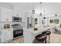 Modern kitchen with white cabinetry, stainless steel appliances, and a sleek island with bar stool seating at 1615 Carlton Ave, Kannapolis, NC 28083