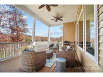 Inviting covered deck featuring wicker furniture and serene lake views perfect for relaxing outdoors at 226 Hermance Ln, Mooresville, NC 28117