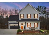 Charming two-story home with a welcoming front porch and craftsman details, set against a beautiful dusk sky at 693 Luther Dr, Iron Station, NC 28080
