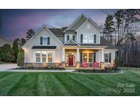 Charming two-story home with a manicured lawn and inviting front porch with bright red chairs at 1005 Palace Ct # 58, Indian Trail, NC 28079