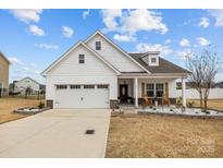Charming, single story home features a manicured lawn, two-car garage, and covered porch with rocking chairs at 1205 Brooksland Pl, Waxhaw, NC 28173