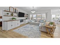 Bright and airy living room featuring a modern fireplace, floating shelves and comfortable seating with a crystal chandelier at 1205 Brooksland Pl, Waxhaw, NC 28173