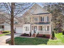 Charming two-story home with a covered front porch and well-maintained lawn and an attached garage at 15124 Hugh Mcauley Rd, Huntersville, NC 28078
