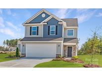 Charming two-story home with a two-car garage, manicured lawn, and colorful flower beds at 15311 Lake Ridge Rd, Charlotte, NC 28278