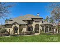 Stunning home featuring a manicured lawn, stone accents, arched entryway, and meticulously maintained landscaping at 16744 Ashton Oaks Dr, Charlotte, NC 28278