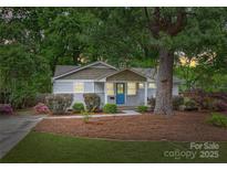 Charming single-story home featuring a blue front door, landscaped yard, and mature trees at 1837 Academy St, Charlotte, NC 28205