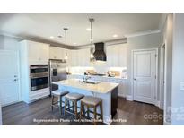 Modern kitchen with white cabinets, stainless steel appliances, a center island with barstool seating, and pendant lighting at 19732-A School St, Cornelius, NC 28031