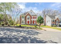 Charming brick two-story home featuring bright red shutters and front door and well-manicured lawn at 6916 Sardis Green Ct, Charlotte, NC 28270