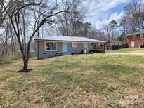 Charming one-story home with a metal roof, baby-blue door, brick facade, and an established yard at 112 Greentree Dr, Mount Holly, NC 28120