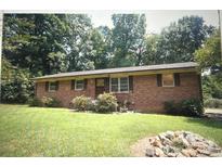 Cozy brick home features mature trees and a lush green front lawn, enhancing its curb appeal at 213 Turner Rd, Gastonia, NC 28056