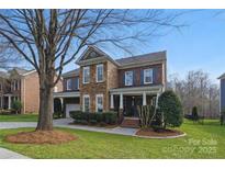 Charming two-story home with a combination of brick and stone exterior, blue shutters, and landscaped front yard at 3203 Thayer Dr, Waxhaw, NC 28173