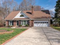 Charming brick home with attached two car garage, beautiful lawn, and inviting entryway at 3274 Roberta Farms Sw Ct, Concord, NC 28027