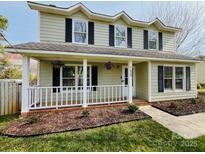 Charming two-story home featuring a welcoming front porch with decorative hanging flower baskets at 7025 Spring Morning Ln, Charlotte, NC 28227