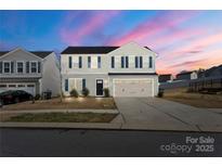 Two-story home with blue shutters, a two-car garage, and a well-manicured front lawn at sunset at 8010 Bruce St, Charlotte, NC 28215