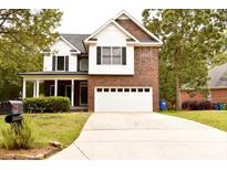 Charming two-story home featuring a brick and white facade, inviting front porch, and a well-manicured lawn at 1120 Millwright Ln, Matthews, NC 28104
