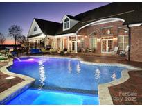 A luxurious outdoor pool and patio area create an inviting space for relaxation and entertainment at twilight at 49461 River Run Rd, Albemarle, NC 28001