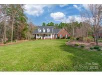 Charming brick home featuring a well-manicured lawn, lush trees, and a welcoming front porch at 514 Saint Johns Dr, Salisbury, NC 28144