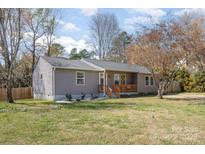 Charming single-story home with a well-maintained yard, inviting front porch, and mature trees at 9105 Touchstone Ln, Charlotte, NC 28227