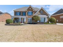 Beautiful two-story home featuring a brick and stone facade, manicured landscaping, and a welcoming covered front porch at 10005 Chimney Dr, Waxhaw, NC 28173