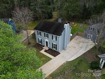 Inviting two-story home with a well-kept lawn, complemented by lush greenery and a long driveway at 12109 Sawtry Ct, Pineville, NC 28134