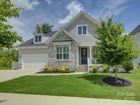 Charming two-story home with a stone facade, well-manicured lawn, and a welcoming front porch at 14230 Morningate St, Huntersville, NC 28078