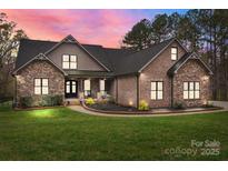 Charming brick and stone home with a well-manicured lawn and inviting front porch, blending elegance with comfort at 1770 Cranwell Dr, Mt Ulla, NC 28125