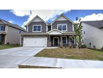 Charming two-story home featuring a stone facade, covered porch, two-car garage, and professionally landscaped yard at 113 Asmodean Ln, Troutman, NC 28166