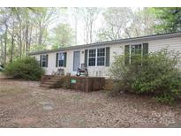 Charming single-story home with a brick foundation and a cozy front porch surrounded by mature trees at 7597 Webbs Rd, Denver, NC 28037