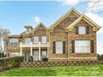 Charming brick two-story home with landscaped yard and inviting front porch with white columns at 1110 Woodhall Dr, Huntersville, NC 28078