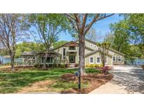 Stunning two-story home boasts a beautiful lawn, mature trees, and a charming front entrance on a sunny day at 19528 Mary Ardrey Cir, Cornelius, NC 28031