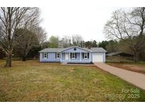 Charming single-story home featuring a light blue exterior, well-maintained landscaping, and a covered parking area at 2225 Grace Church Rd, Salisbury, NC 28147