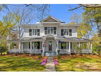 Charming two-story home with a large wrap-around porch, manicured lawn, and mature trees, perfect for outdoor living at 121 N Congress St, York, SC 29745