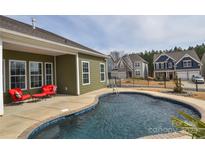 Beautiful in-ground pool with patio, red lounge furniture and attractive homes in the background at 1638 Sweetmoss Loop, Denver, NC 28037