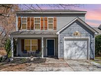 Charming two-story home featuring a one-car garage, landscaped yard, and inviting front porch with seating at 2709 Reid Meadows Dr, Charlotte, NC 28208