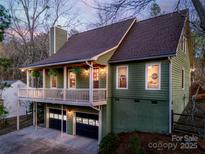 Inviting exterior featuring a spacious balcony, two-car garage, and a charming green facade at dusk at 6008 Lanai Ln, Tega Cay, SC 29708