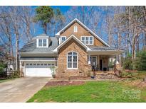 Charming home showcasing a stone and shingle facade, complemented by a manicured lawn and attached two-car garage at 7806 Spanish Oaks Dr, Waxhaw, NC 28173