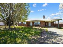 Charming brick home with a metal roof, carport and a lush green lawn at 976 Pointview Ln, Lincolnton, NC 28092