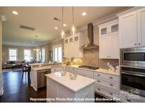Bright kitchen boasts white cabinets, stainless steel appliances, pendant lighting and center island at 19724-A School St, Cornelius, NC 28031