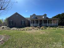 Charming brick home with a covered porch, dormers, and a well-manicured front yard with flower beds at 3615 Wellman Rd, Vale, NC 28168