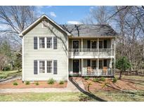 Charming two-story home featuring a double front porch with chairs and a well-manicured lawn at 7500 Soaringfree Ln, Charlotte, NC 28226