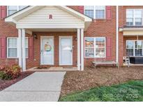 Brick townhome exterior with a covered front entrance, colorful door wreath, and landscaped yard at 102 Brandywine Ne Dr # R3, Conover, NC 28613