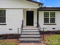 Inviting front entrance featuring a painted brick facade, contrasting black door, and well-maintained steps with iron railings at 5316 Rupert Ln, Charlotte, NC 28215