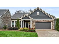 Charming home exterior featuring stone accents, a two-car garage, manicured lawn, and a welcoming covered front entrance at 7909 Parknoll Dr, Huntersville, NC 28078