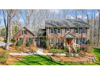 Charming brick home featuring a well-manicured front yard and inviting entryway with mature trees and landscaping at 9951 Providence Forest Ln, Charlotte, NC 28270